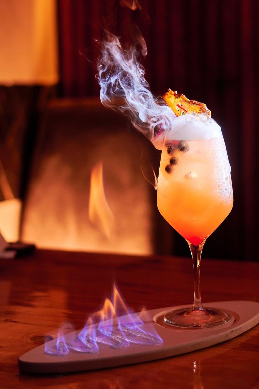 Smoking cocktail with flames on a wooden table